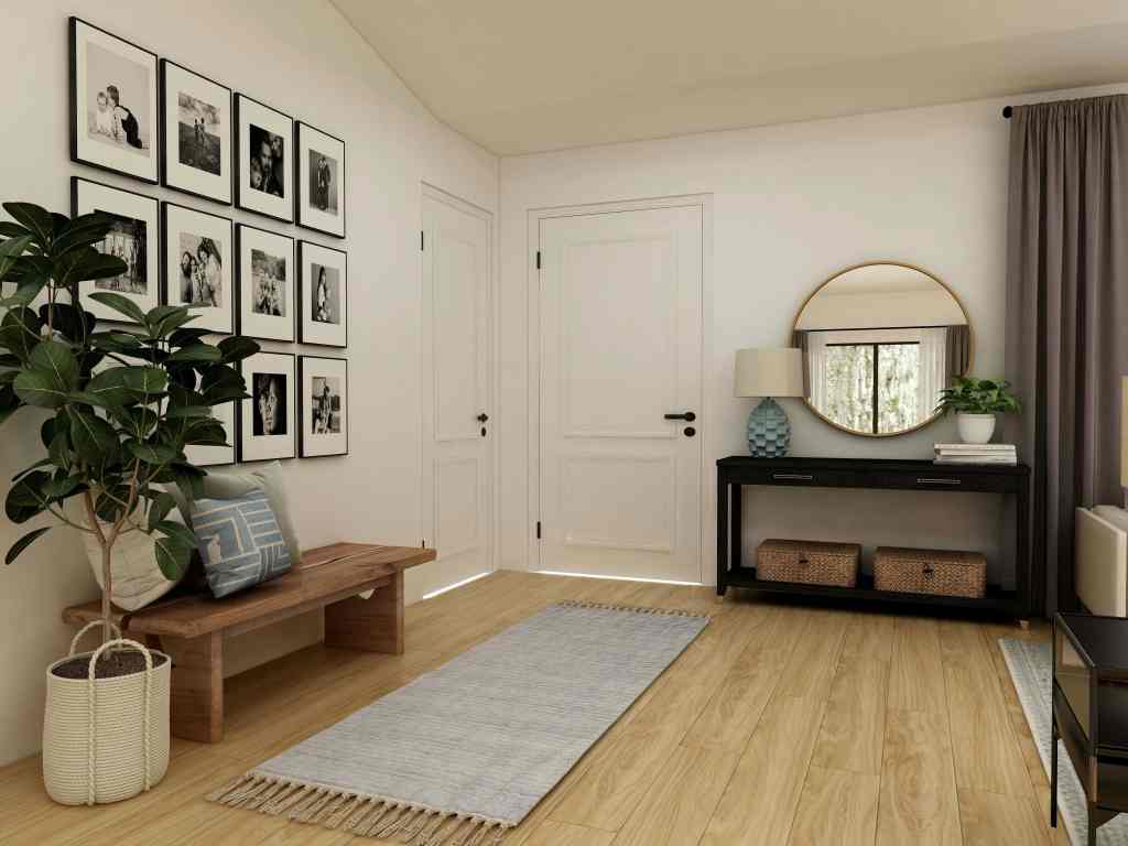A modern entryway featuring a wooden bench, potted plant, black and white photo gallery on the wall, a round mirror, and a stylish console table with decorative items.